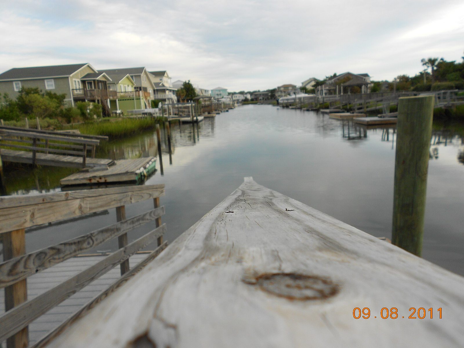 A calm canal behind Holden Beach homes, with docks and a wooden walkway